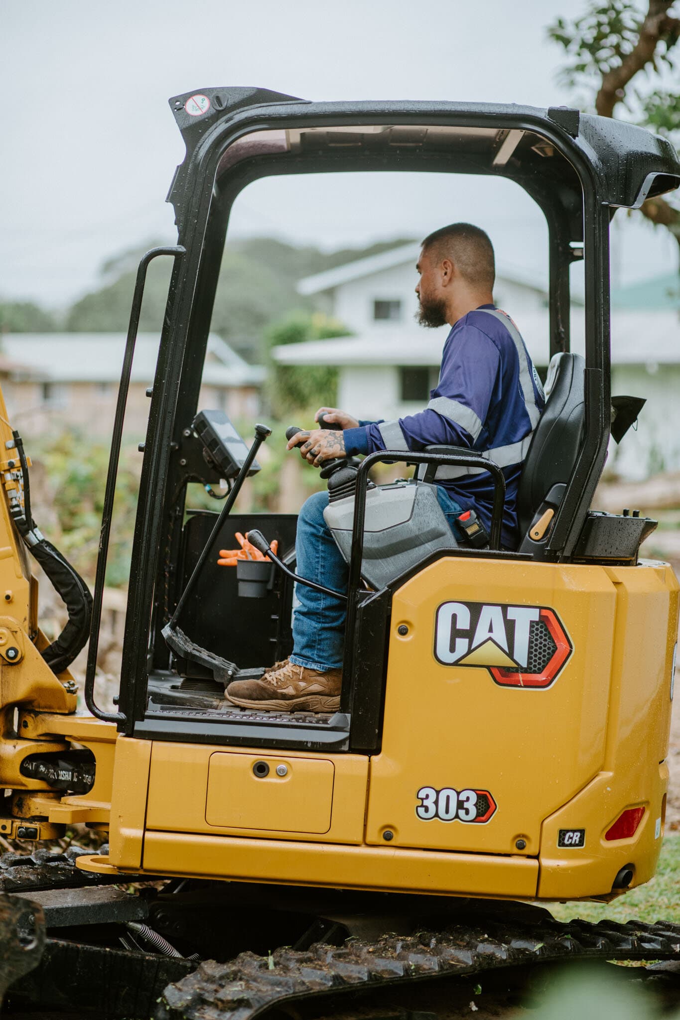 Naea Kaopua operating a CAT 303 mini excavator on a Hilo residential job