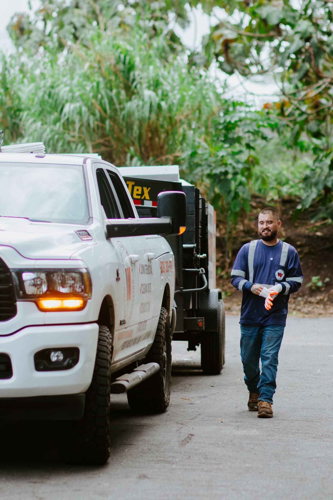 Naea Kaopua walking with the Hawaii Island Waste truck at a residential cleanout