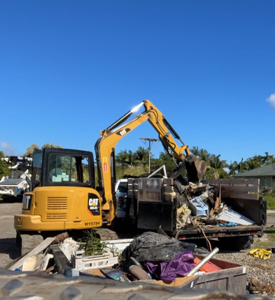 Hawaii Island Waste CAT excavator loading demolition debris into a hauling truck on a Hawaiʻi Island jobsite