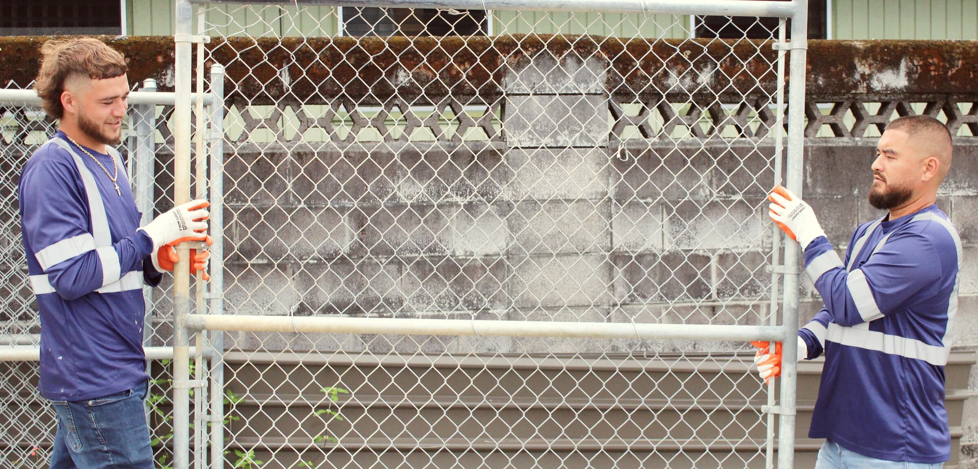 Hawaii Island Waste crew carrying out a chain-link fence panel during a demolition project